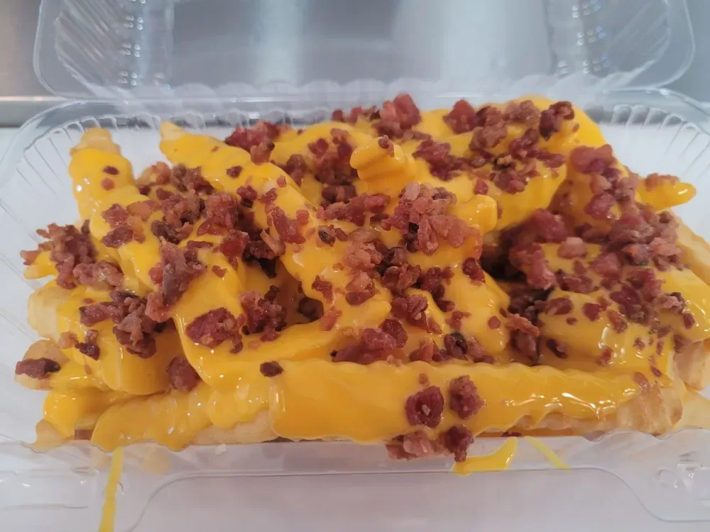 Bacon cheese fries with warm cheddar cheese sauce and bacon in an oblong tray